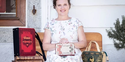 Händler - überwiegend regionale Produkte - PLZ 4463 (Österreich) - Künstlerin Bernadette Hartl mit ihren Taschen aus Büchern vor ihrem Atelier sitzend in Steyr. - Bernanderl Upcycling