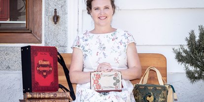 Händler - Zahlungsmöglichkeiten: PayPal - Thann (Dietach) - Künstlerin Bernadette Hartl mit ihren Taschen aus Büchern vor ihrem Atelier sitzend in Steyr. - Bernanderl Upcycling