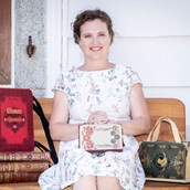 Unternehmen - Künstlerin Bernadette Hartl mit ihren Taschen aus Büchern vor ihrem Atelier sitzend in Steyr. - Bernanderl Upcycling