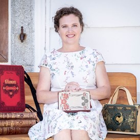 Unternehmen: Künstlerin Bernadette Hartl mit ihren Taschen aus Büchern vor ihrem Atelier sitzend in Steyr. - Bernanderl Upcycling